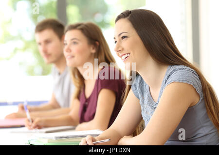 Drei aufmerksame Schüler hören zu einer Lektion in einem Klassenzimmer Stockfoto