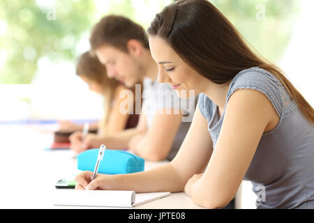 Konzentrierter Schüler Notizen in einem Klassenzimmer mit Klassenkameraden im Hintergrund Stockfoto