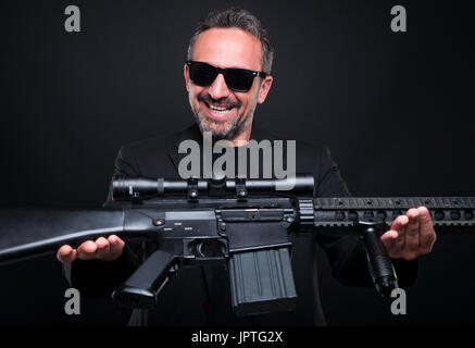 Mafia Gangster seine Waffe als illegalen Deal Konzept auf dunklem Hintergrund zu verkaufen Stockfoto