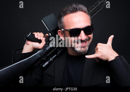 Mafia-Händler verkaufen gefährlich Maschinengewehr als illegalen Handel Konzept und tun Anruf Geste hand Stockfoto