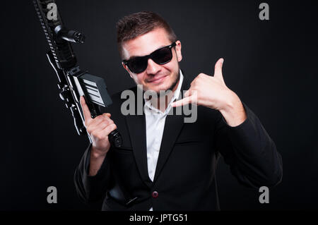 Junge Amokläufer, die illegalen Handel mit Waffe und Rufzeichen Geste zeigt Stockfoto