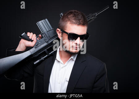 Hübscher junger Mann hält eine Waffe auf der Schulter als Körperverletzung und Tod Konzept Stockfoto