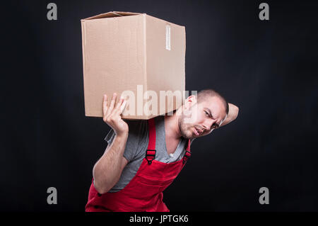 Mover Mann mit schweren Karton auf schwarzem Hintergrund Stockfoto