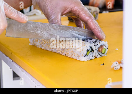 Nahaufnahme der Koch die Hände Vorbereitung japanischen Essen. Sushi Restaurant machen. Junge mit traditioneller serviert auf einem schwarzen Steinplatte Stockfoto
