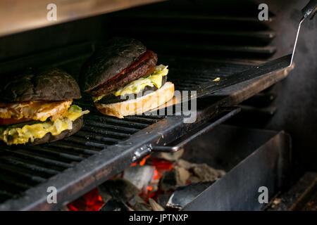 Männliche Koch bereitet Burger. Ein Burger vom Herd nimmt. Stockfoto