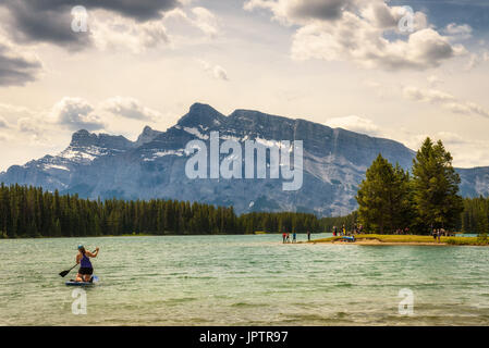 Touristen genießen einen sonnigen Tag am See im Banff National Park mit Mt. Rundle zwei Jack im Hintergrund. Stockfoto