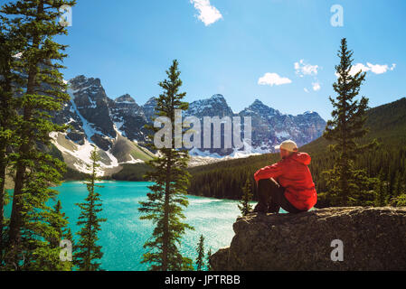 Wanderer genießen die Aussicht auf Moraine Lake im Banff Nationalpark, Alberta, Kanada, mit Schnee bedeckten Gipfeln der kanadischen Rocky Mountains im Hintergrund Stockfoto