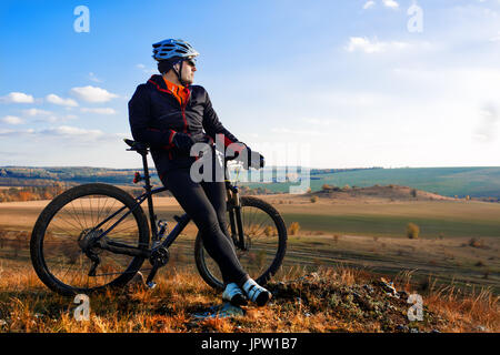 Mann in Helm und Brille Aufenthalt auf dem Fahrrad unter Himmel mit Wolken. Stockfoto