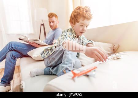 Seitenansicht des fokussierten kleiner Junge spielt mit Spielzeug mit Vater hinter Stockfoto