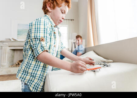 Seitenansicht des fokussierten kleiner Junge spielt mit Spielzeug mit Vater hinter Stockfoto