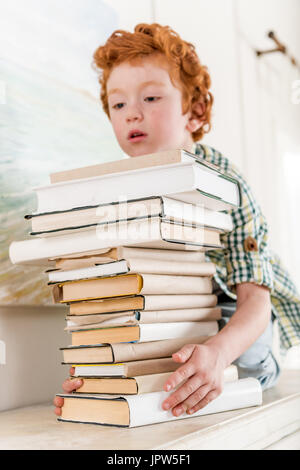 Porträt von fokussierten kleiner Junge hält Stapel Bücher Stockfoto