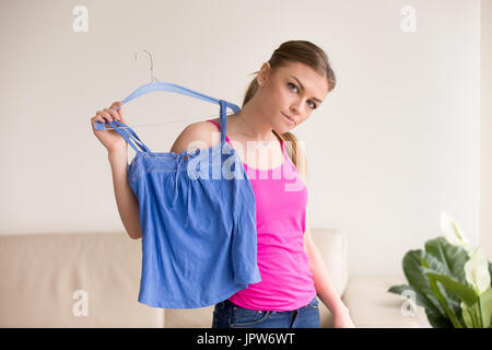 Nachdenklich Dame stehend mit Bluse auf Kleiderbügel Stockfoto