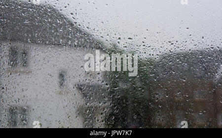 Blick durch ein Regentropfen überdachte Fenster in Häusern an einem regnerischen Sommertag Stockfoto