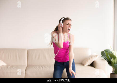 Frau im Kopfhörer singen und tanzen zu Hause Stockfoto