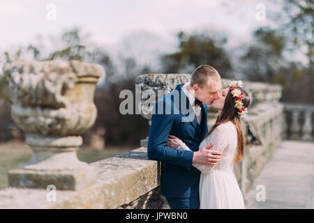 Porträt von stilvollen Brautpaar leidenschaftlich küssen an alte Steinterrasse in Frühlingspark Hochzeit Stockfoto