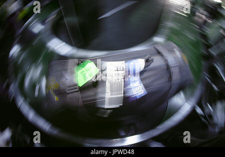 Gepäckausgabe Karussell mit großen schwarzen Koffer mit USA Gepäckanhänger und eine gelbe x-ray-Label in der Ankunftshalle, Bewegung-verschwommenes Bild Stockfoto