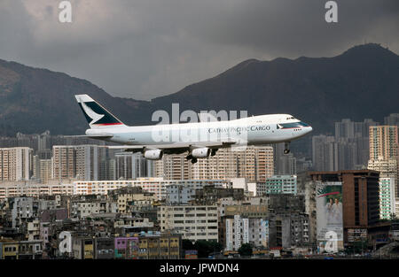 Cathay Pacific Cargo Boeing 747-200BSF auf Finale-Anflug auf die Piste 13 mit Kowloon Wolkenkratzer und Hügeln hinter Stockfoto