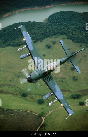 Brasilianische Luftwaffe Embraer EMB 314 Super Tucano Banking über Fluss, Felder und Bäume Stockfoto