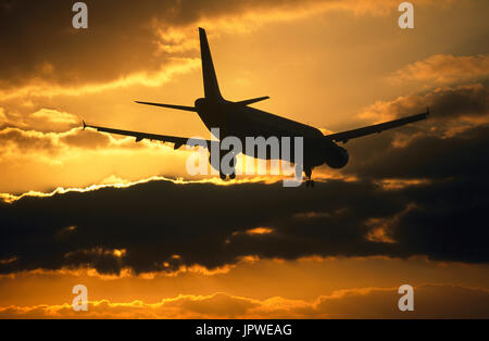 Airbus A320 auf Finale-Ansatz in der Abenddämmerung mit goldenen Himmel und dunkle Wolken hinter Stockfoto