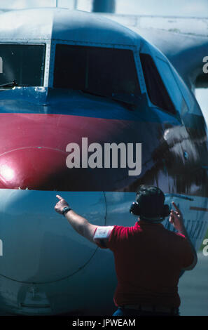 Flughelfer mit Gehörschutz Signalisierung zum pilot Motoren auf einem USAir Express DHC-7 Dash 7 starten Stockfoto