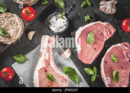 Rohe Bio-Fleisch. Auswahl von mehreren Arten von rotem Fleisch: Schweineschnitzel auf Knochen, Steaks von Schwein und Huhn Schnitzel im Raster von Schweinefett. Mit Zutaten f Stockfoto