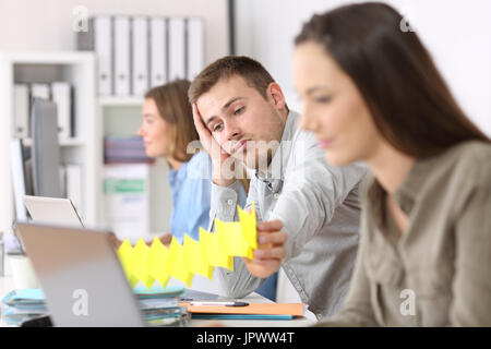 Porträt eines faulen Mitarbeiter sitzen in einem Desktop zwischen den anderen Arbeitnehmern im Büro langweilig Stockfoto