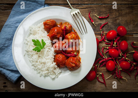 Fleischbällchen in Tomatensauce mit gekochtem Reis und rote Chilischote Stockfoto