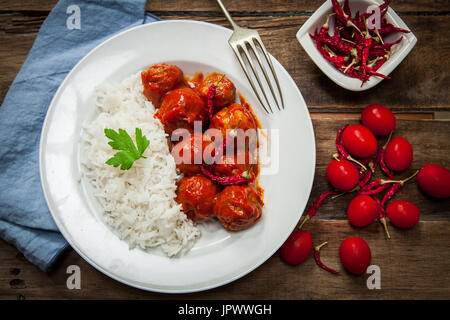 Fleischbällchen in Tomatensauce mit gekochtem Reis und rote Chilischote Stockfoto