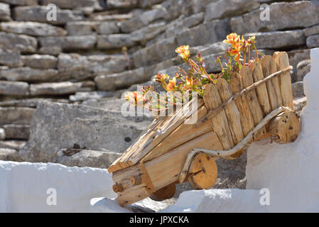 Holz Blumentopf mit bunten Flowerson alte äußere Steinhaus in Nahaufnahme Stockfoto