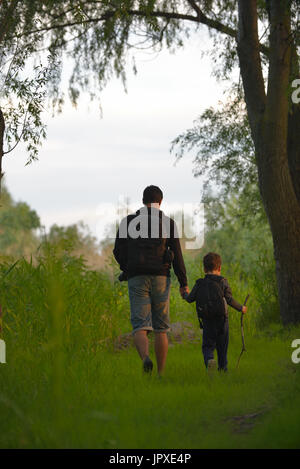 Vater und Sohn gehen auf eine Reise in die Welt des Forrest bei Sonnenuntergang Stockfoto