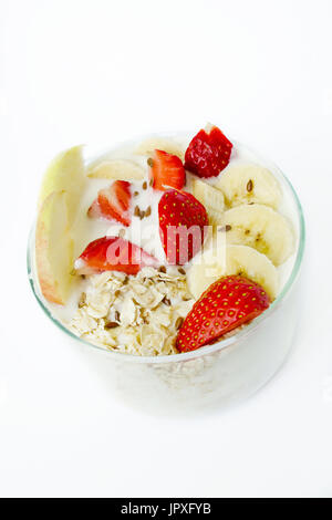 Gesundes Frühstück - Joghurt, Haferflocken, Leinsamen, Erdbeeren, Bananen, Äpfel. Weißen Hintergrund. Vertikale Foto Stockfoto