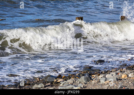 Wellen über Wellenbrecher auf einem felsigen Strand bei Llanfairfechan, North Wales. Das Bild wurde am 14. September 2013 getroffen Stockfoto