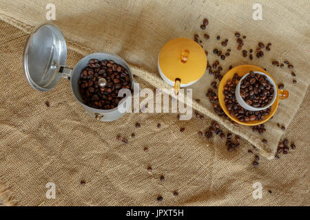 Tavigliano, Italien - 1. August 2017: Hohe Winkelrahmen über italienischen Moka und Kaffeebohnen in die Tasse. Vintage Still Life-Style, Jute-Tasche im staatlich Stockfoto