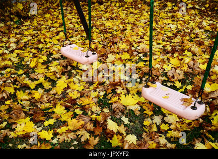 Wippen Sie auf dem Spielplatz mit Herbstlaub abgedeckt Stockfoto