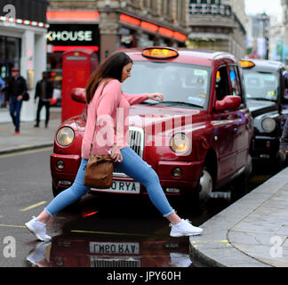 Frau stieg über Pfütze infront von Taxi in London Stockfoto