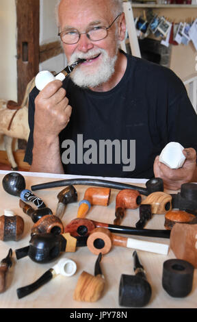 Pfeifenmachers Peter Lehmann sitzt mit verschiedenen Tabakpfeifen in seiner Lehmann-Werkstatt, die er zusammen mit seiner Frau, Holz Designer Martina Abicht-Lehmann, seit 1989 in Hausdorf bei Colditz, Deutschland, 28. Juni 2017 läuft. Der passionierte Pfeifenraucher produziert seit vielen Jahren handgefertigte Pfeifen aus Meerschaum Stein, Ebenholz, Mooreiche, Olivenholz oder Briarwood gemacht die fertigen nach individuellen Wünschen des Kunden und finden ihren Weg zu vielen Destinationen auf der ganzen Welt rauchen. Von den ca. 2500 Pfeifen, die er produzierte, einige fanden ihren Weg nach Hollywood und Babelsberg.Colditz, Stockfoto