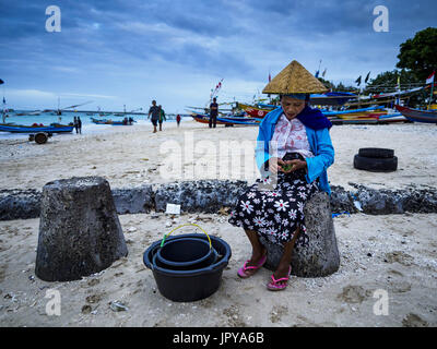 Kuta, Bali, Indonesien. 3. August 2017. Eine Frau wartet, Fisch vom Fischer wieder aus dem Ozean auf Jimbrana Strand in Kuta zu kaufen. Der Strand liegt in der Nähe des Flughafens und eine kurze Autofahrt von den anderen Stränden im Südosten Bali. Jimbrana war ursprünglich ein Fischerdorf mit einem geschäftigen Markt. Vor etwa 25 Jahren Entwickler begann mit dem Bau von Restaurants und Hotels entlang der Strand und Land Preise steigen. Der neue Schwerpunkt auf Tourismus verändert sich die Natur der Gegend, aber die Fischer sind noch damit beschäftigt, in den sehr frühen Morgenstunden. Bildnachweis: Jack Kurtz/ZUMA Draht/Alamy Live-Nachrichten Stockfoto
