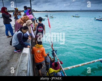 Kuta, Bali, Indonesien. 3. August 2017. Frauen warten auf dem Steg, wie ihre Ehemänner aus einem Trawler auf dem Steg am Jimbrana Strand in Kuta zurück ans Ufer kommen. Der Strand liegt in der Nähe des Flughafens und eine kurze Autofahrt von den anderen Stränden im Südosten Bali. Jimbrana war ursprünglich ein Fischerdorf mit einem geschäftigen Markt. Vor etwa 25 Jahren Entwickler begann mit dem Bau von Restaurants und Hotels entlang der Strand und Land Preise steigen. Der neue Schwerpunkt auf Tourismus verändert sich die Natur der Gegend, aber die Fischer sind noch damit beschäftigt, in den sehr frühen Morgenstunden. Bildnachweis: Jack Kurtz/ZUMA Draht/Alamy Live-Nachrichten Stockfoto