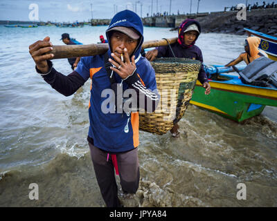 Kuta, Bali, Indonesien. 3. August 2017. Männer nehmen Fische gefangen auf einem Trawler aus einem Kanu, die Besatzungsmitglieder und Haken zwischen die Trawler und Ufer am Jimbrana Strand in Kuta pendelt. Der Strand liegt in der Nähe des Flughafens und eine kurze Autofahrt von den anderen Stränden im Südosten Bali. Jimbrana war ursprünglich ein Fischerdorf mit einem geschäftigen Markt. Vor etwa 25 Jahren Entwickler begann mit dem Bau von Restaurants und Hotels entlang der Strand und Land Preise steigen. Der neue Schwerpunkt auf Tourismus verändert sich die Natur der Gegend, aber die Fischer sind noch damit beschäftigt, in den sehr frühen Morgenstunden. (Kredit-Bild: © Jack Kurt Stockfoto