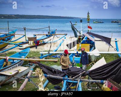 Kuta, Bali, Indonesien. 3. August 2017. Fischer gehen unter den gestrandeten Outrigger-Kanus am Jimbrana Strand in Kuta. Der Strand liegt in der Nähe des Flughafens und eine kurze Autofahrt von den anderen Stränden im Südosten Bali. Jimbrana war ursprünglich ein Fischerdorf mit einem geschäftigen Markt. Vor etwa 25 Jahren Entwickler begann mit dem Bau von Restaurants und Hotels entlang der Strand und Land Preise steigen. Der neue Schwerpunkt auf Tourismus verändert sich die Natur der Gegend, aber die Fischer sind noch damit beschäftigt, in den sehr frühen Morgenstunden. Bildnachweis: Jack Kurtz/ZUMA Draht/Alamy Live-Nachrichten Stockfoto