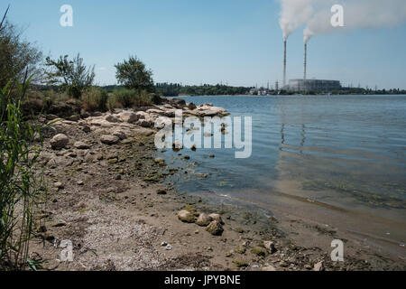 Im Sommer gibt es sehr wenig Wasser im Fluss Südlicher Bug in der Nähe der Stadt Ladyzhin wegen des heißen Wetters und der Unternehmen nehmen Sie Wasser für ihre Bedürfnisse. Im Hintergrund ist ein Kraftwerk. Stockfoto