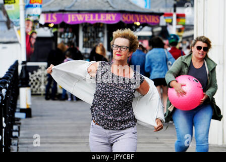 Brighton, UK. 3. August 2017. Eine Frau kämpft mit ihrem Fleece-Jacke in den starken Winden auf Brighton Seafront wie das unbesiedelte Sommerwetter an der Südküste weiter, aber es wird voraussichtlich um in den nächsten Tagen Credit zu verbessern: Simon Dack/Alamy Live News Stockfoto