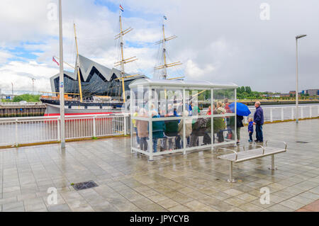 Glasgow, Schottland. 3. August 2017. Großbritannien Wetter. Passagiere warten an den Ufern des Flusses Clyde für die Govan Fähre zu nehmen sie über das Riverside Museum und Großsegler, lebhafteste, an einem sonnigen Tag mit teils sonnig und häufige schwere Duschen Credit: Skully/Alamy Live News Stockfoto
