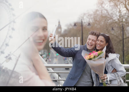 Begeisterten paar mit Blumenstrauß nehmen Selfie mit Kamera-Handy auf städtische Brücke, London, UK Stockfoto