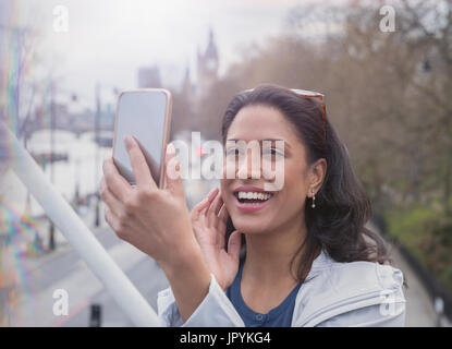 Lächelnd, selbstbewusste Frau, die unter Selfie mit Kamera-Handy auf städtische Brücke Stockfoto