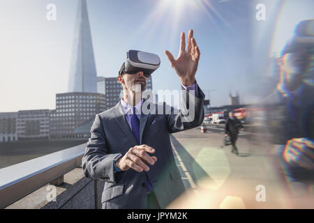 Geschäftsmann mit virtual-Reality-Simulator Gläser auf sonnigen städtische Brücke, London, UK Stockfoto