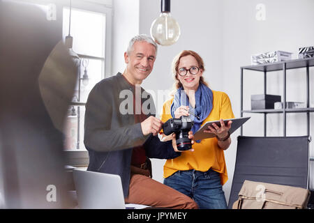 Porträt, Lächeln, zuversichtliche Fotografen mit Digitalkamera und digitale Tablet im Büro Stockfoto