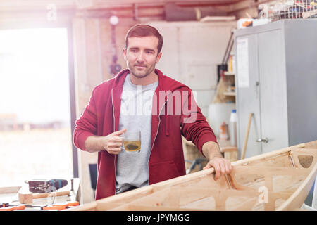 Männliche Zimmermann, Tee zu trinken, so dass Holz-Boot in Werkstatt Stockfoto