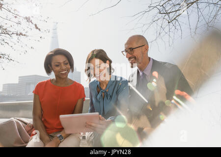 Geschäftsleute, die mit digital-Tablette in sonnigen Stadtpark Stockfoto