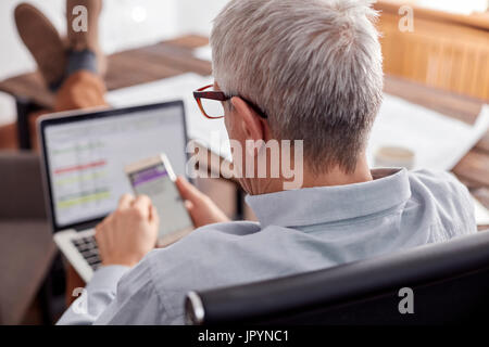 Geschäftsmann, arbeiten, mit Handy und Laptop im Büro Stockfoto